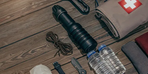 Emergency kit with water, first aid, flashlight, tools, and blanket.